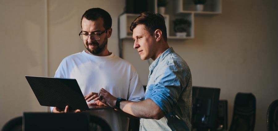 Two engineers reviewing work together on a laptop